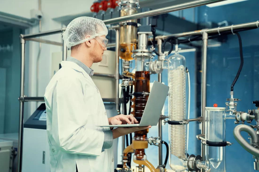 apothecary-scientist-working-with-laptop-near-cbd-oil-extractor-laboratory