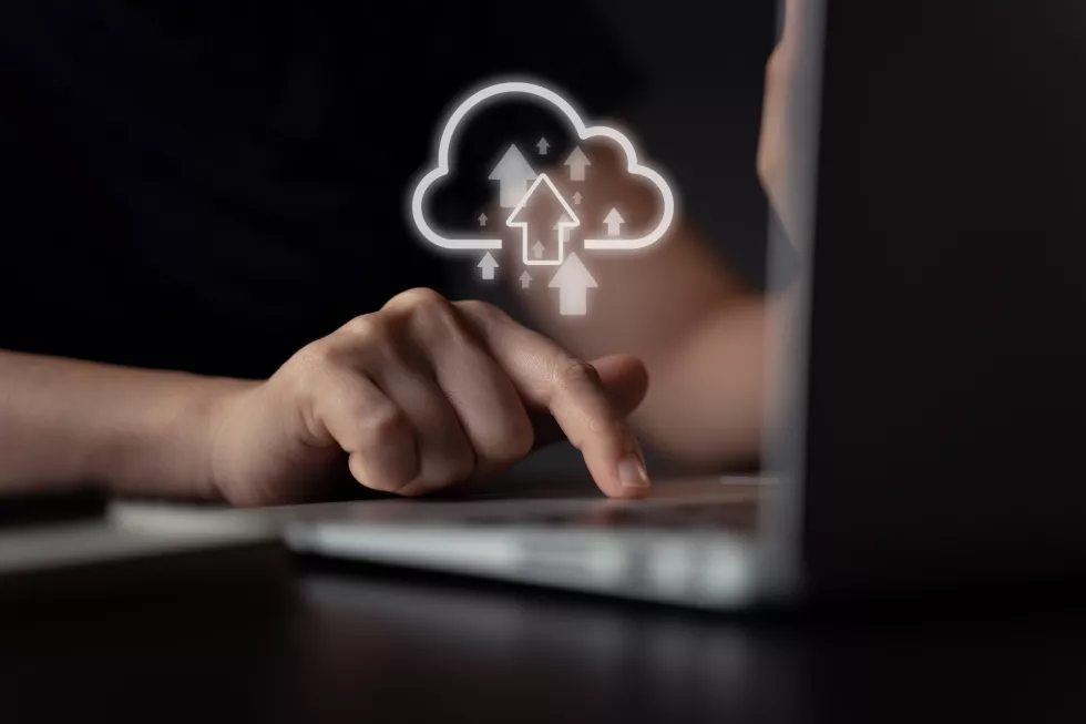 woman-using-laptop-upload-with-cloud-icon-hologram-effect