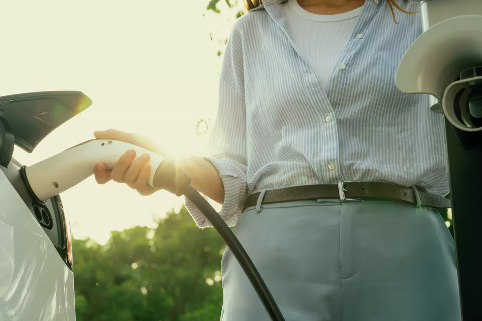 young-woman-recharging-battery-electric-car-road-trip-exalt