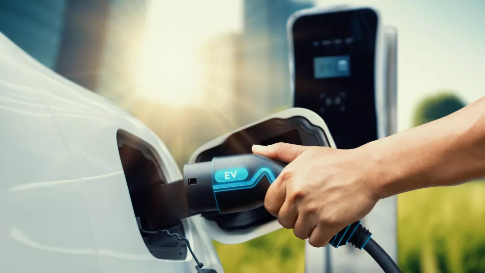 hand-insert-ev-charger-recharge-electric-car-from-charging-station-displaying-futuristic-battery-status-hologram-esg-green-city-park-background-smart-sustainable-clean-energy-peruse