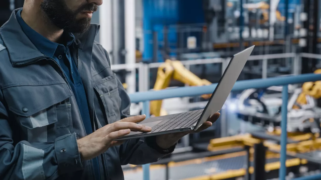 close-up-automotive-industry-engineer-grey-uniform-using-laptop-car-factory-facility-professional-assembly-plant-specialist-working-manufacturing-modern-electric-vehicles