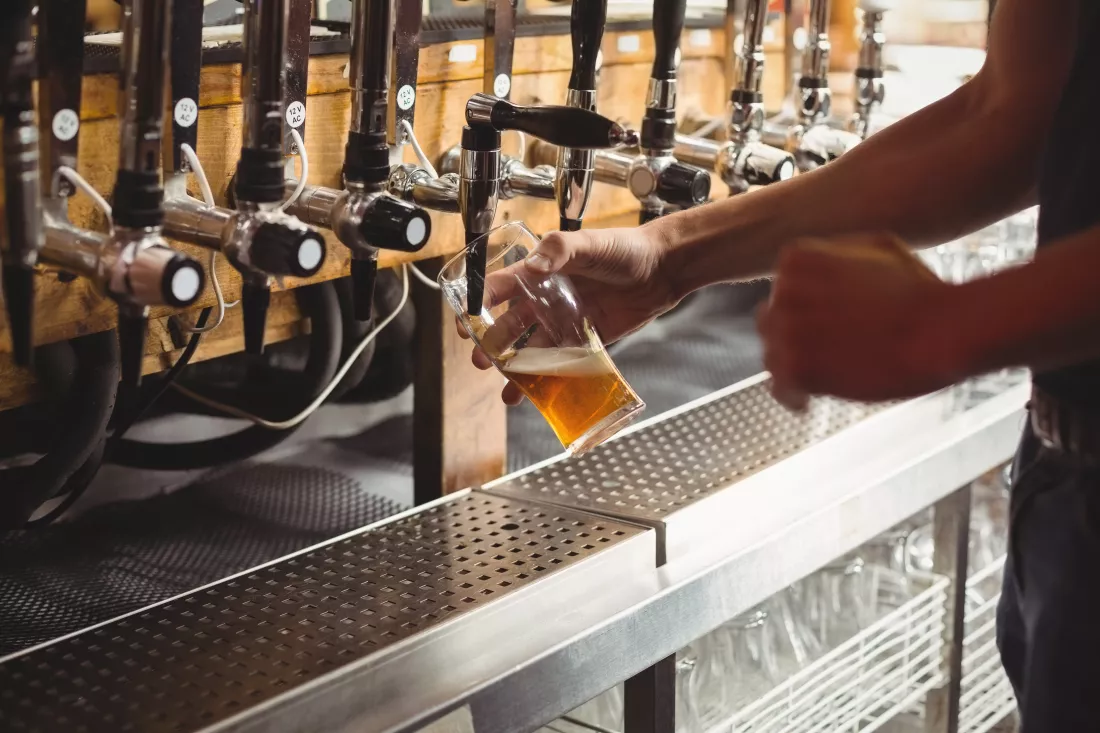 mid-section-bar-tender-filling-beer-from-bar-pump
