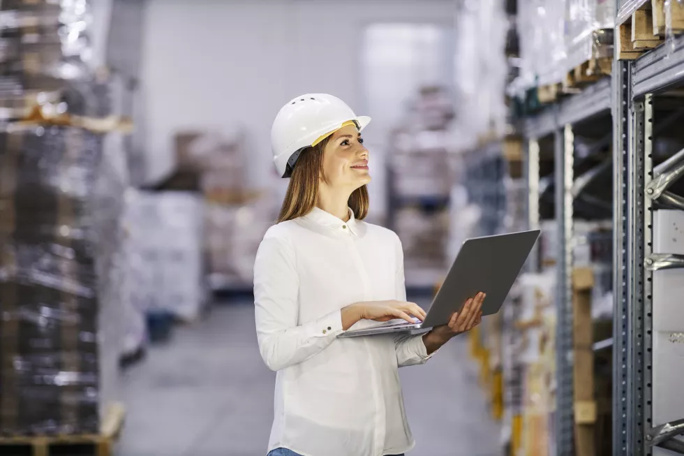 successful-sales-manager-is-entering-data-her-computer-while-standing-factory-warehouse