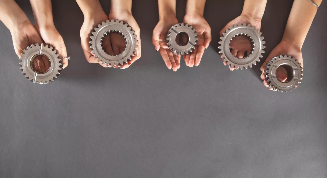 people-holding-gears-business-teamwork