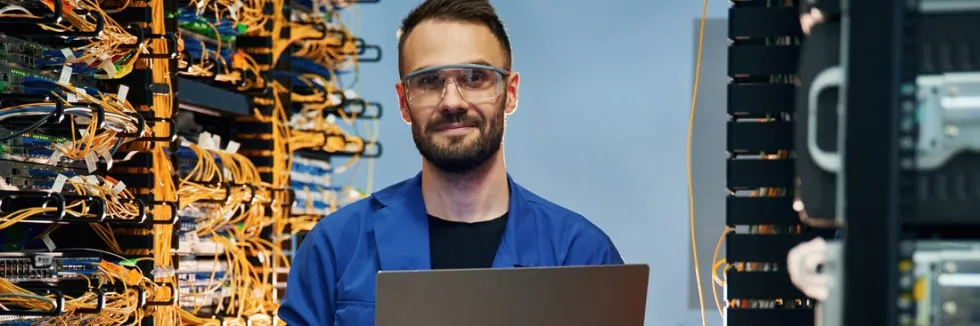 computer-systems-and-network-engineering-usmiechniety-inzynier-sieci-z-laptopem-w-serwerowni