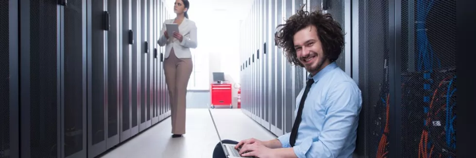 databases-usmiechniety-informatyk-z-laptopem-w-centrum-danych