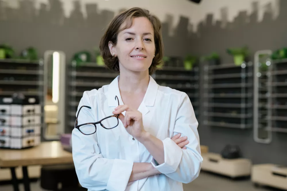 professional-female-optometrist-whitecoat-holding-pair-new-eyeglasses-optics-shop-environment