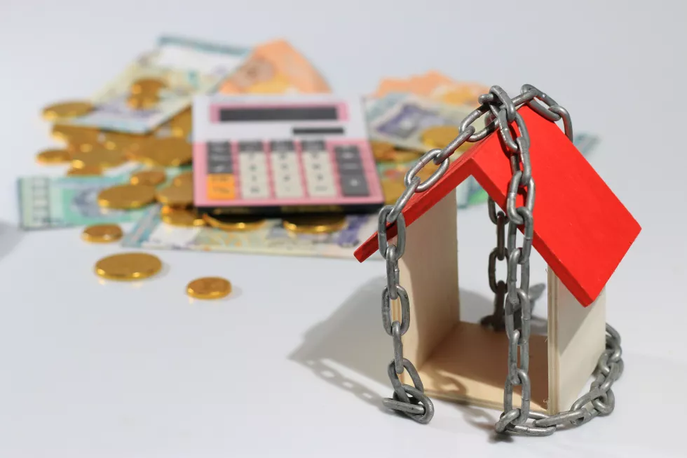 high-angle-view-model-home-with-chain-by-paper-currency-coins-against-white-background