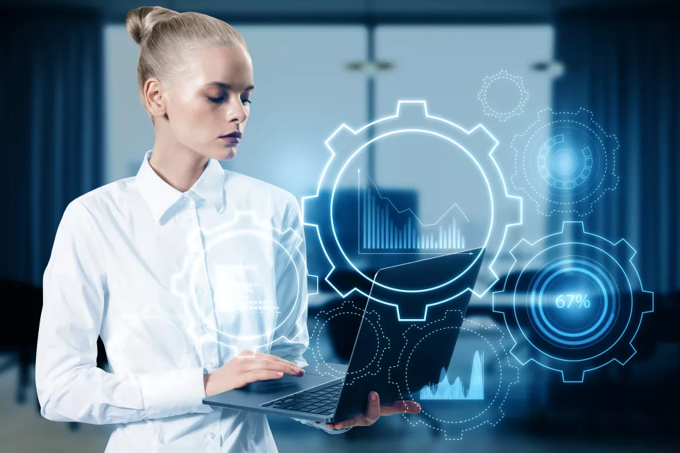 attractive-young-european-businesswoman-with-laptop-glowing-cogwheel-chart-hologram-blurry-office-interior-background-business-analytics-finance-concept-double-exposure