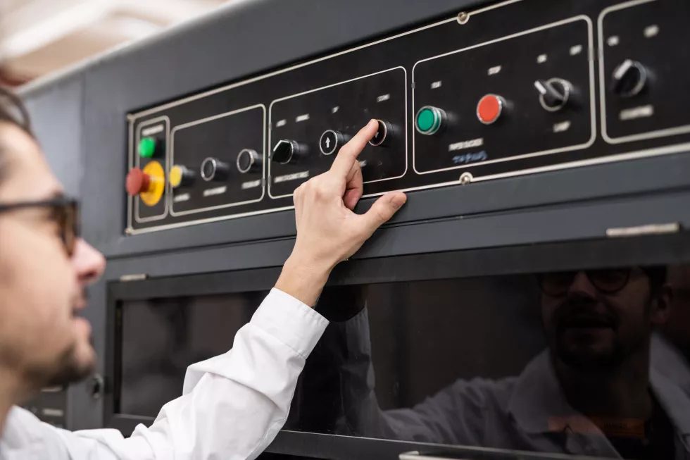 shoulder-view-young-operator-pushing-button-control-panel-while-working-automated-industry