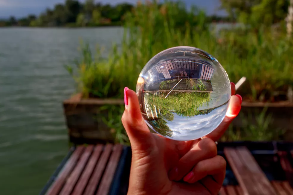cropped-hand-holding-crystal-ball-with-upside-down-reflection-grass-sky