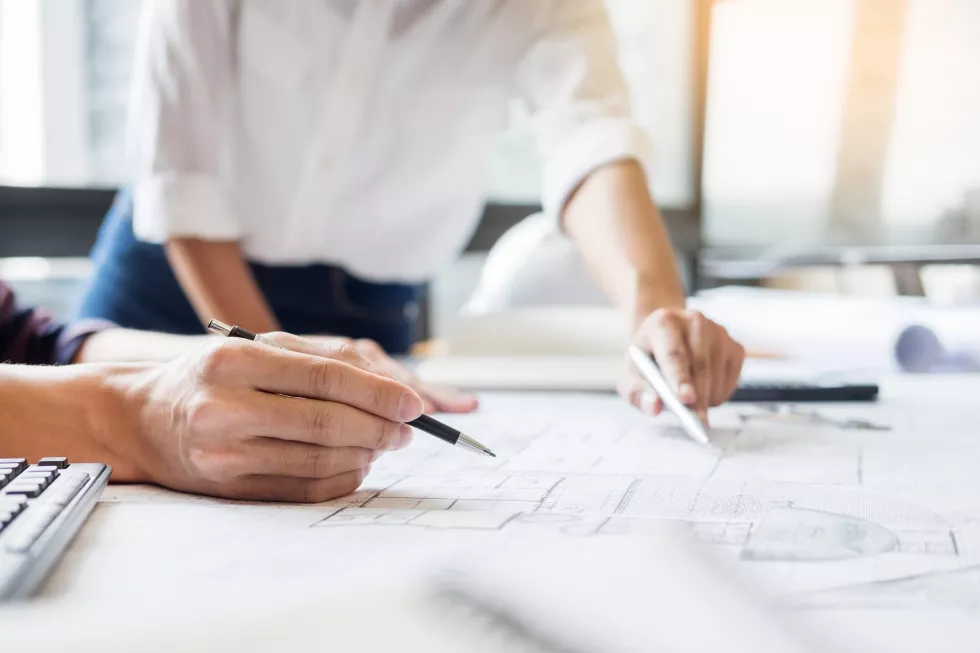midsection-architects-discussing-blueprint-office