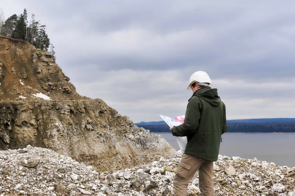 geologist-with-map-near-rocky-river-bank