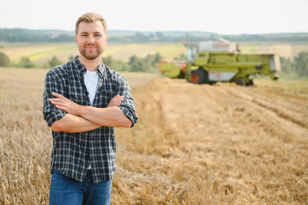 happy-farmer-proudly-standing-field-combine-harvester-driver-going-crop-rich-wheat-harvest-agronomist-wearing-flannel-shirt-looking-camera-farmland
