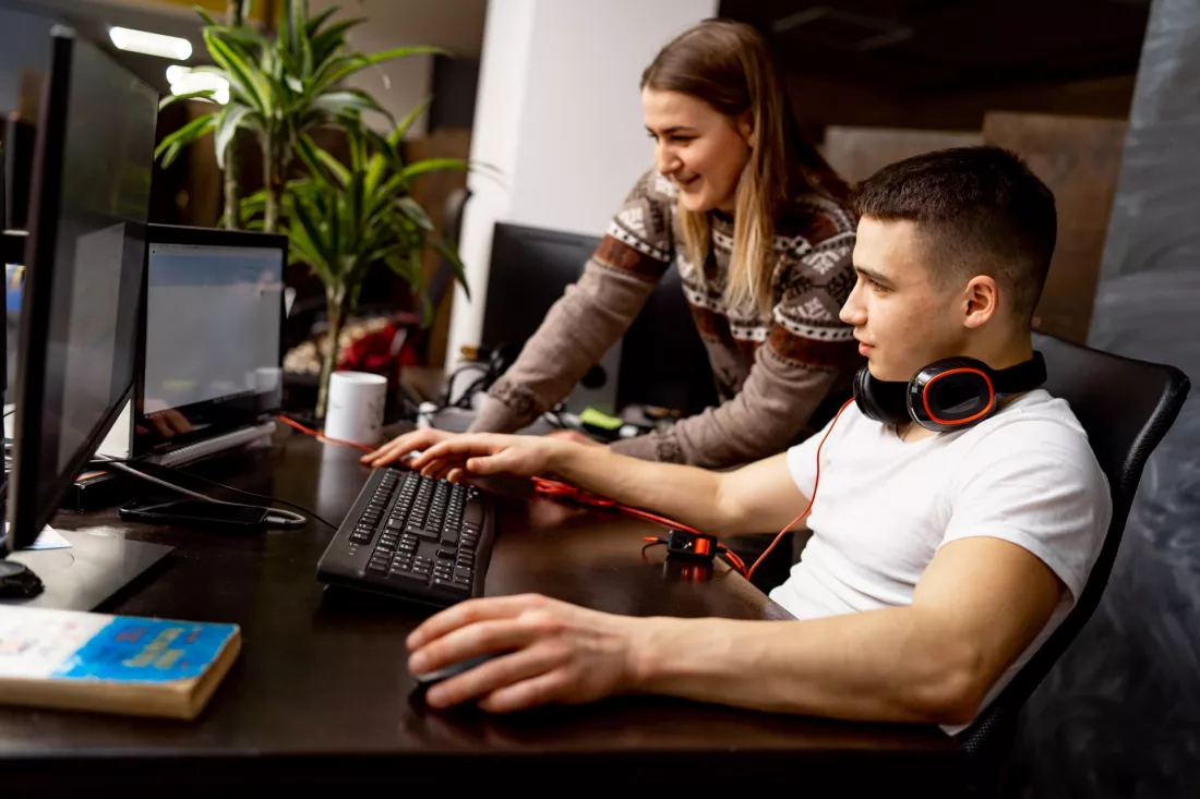 Studenci pracujący nad projektem gry przy komputerach
